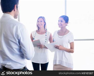 Two young female collegues meeting a new coworker