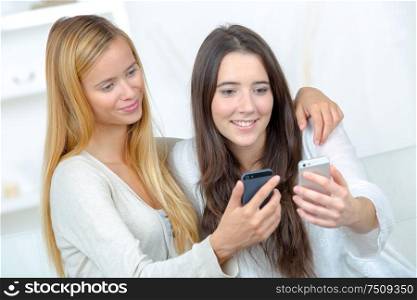 two young female friends check mobile phones