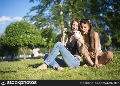 Two young female friends in park taking self portrait on smartphone
