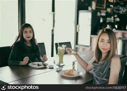 Two young female friends laugh and Having Lunch Together At Restaurant