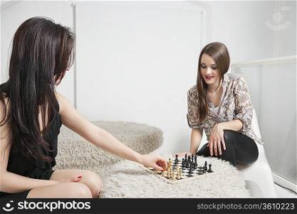 Two young female friends playing chess