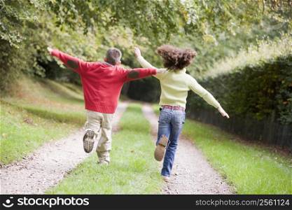 Two young friends running on a path outdoors