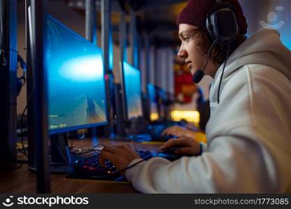 Two young gamers in headsets play in video game club. Virtual entertainment, e-sport tournament, cybersport lifestyle. Two young gamers in headsets play in video game club