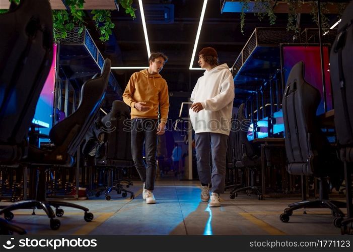 Two young gamers talking in game club. Virtual entertainment, e-sport tournament, cybersport lifestyle. Male person leisures in internet cafe. Two young gamers talking in game club