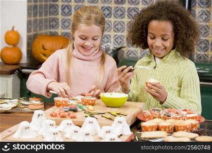 Two young girl friends at Halloween making treats and smiling