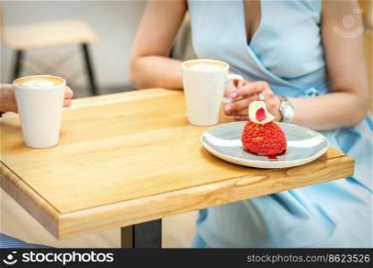 Two young girlfriends drinking coffee with pieces of cake sitting at the table in a cafe outdoors. Two young girlfriends drinking coffee