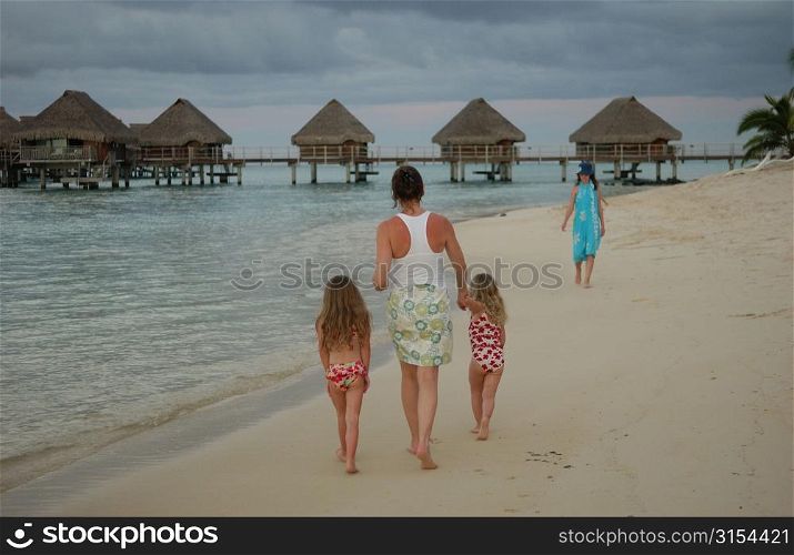 Two young girls (6-8) walking on a beach with their mother, Moorea, Tahiti, French Polynesia, South Pacific