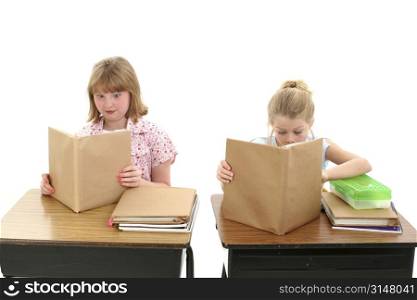 Two young girls at desk reading schoolbook wrapped in brown paper. These are the precut packaged brown paper bookcovers required by some public schools.