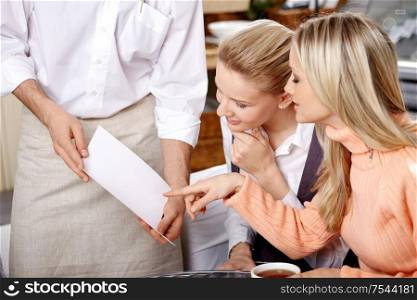 Two young girls choose in the dish menu
