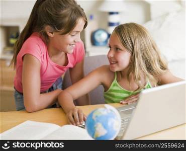 Two Young Girls Doing Homework On A Laptop