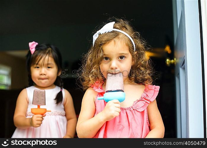 Two young girls eating ice lollies