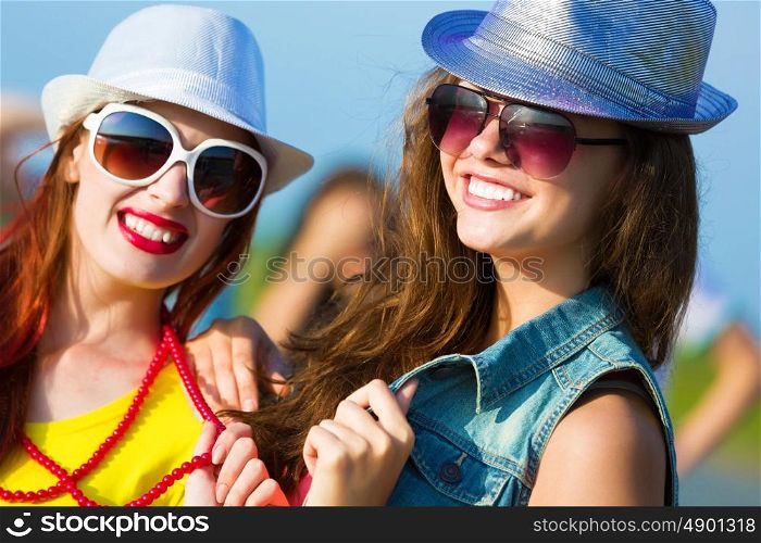 Two young girls. Image of two attractive young women in bright clothes having fun outdoors
