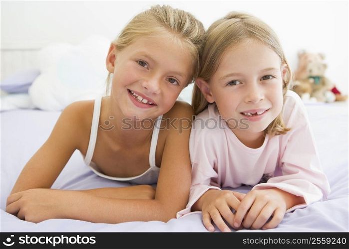 Two Young Girls In Their Pajamas Lying On A Bed