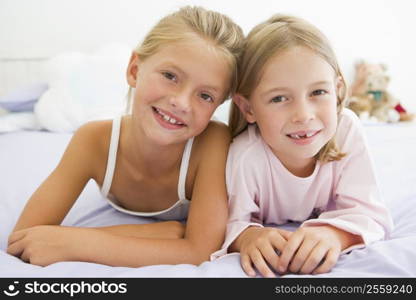 Two Young Girls In Their Pajamas Lying On A Bed