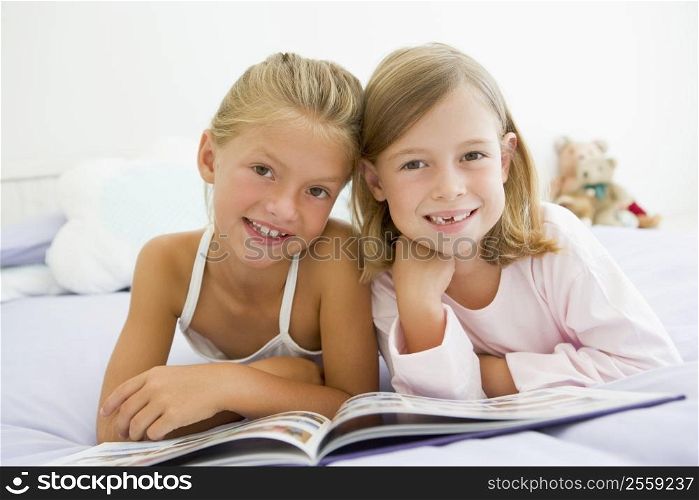 Two Young Girls In Their Pajamas, Reading A Book