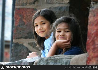 Two young girls looking out of a stone window