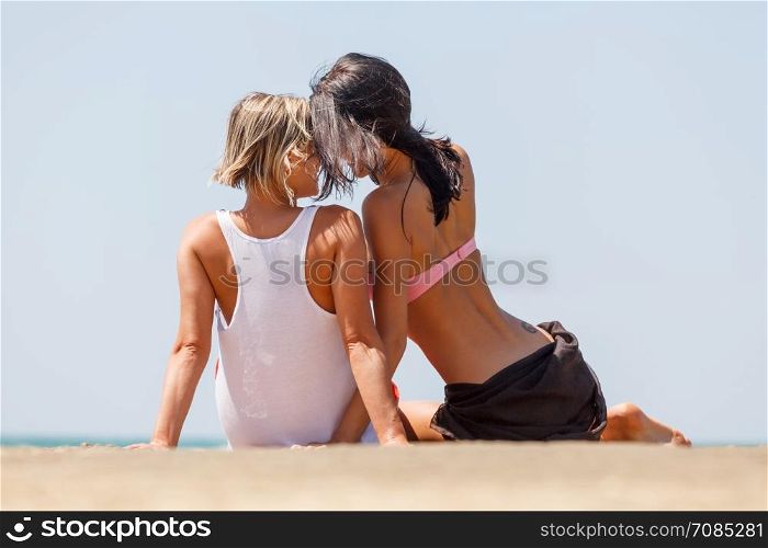 two young girls on natural background. Two young girls having fun chatting on the beach by the sea