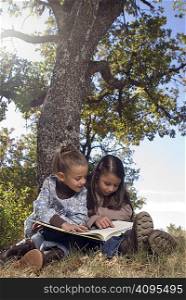 Two young girls reading a book