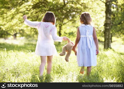 Two Young Girls Walking Through Summer Field Carrying Teddy Bear