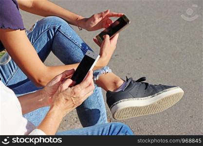 Two young girls watching smart mobile phones