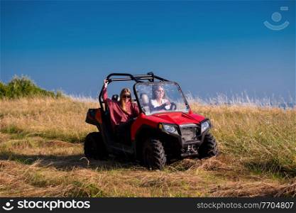 two young happy excited women enjoying beautiful sunny day while driving a off road buggy car on mountain nature
