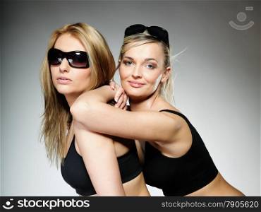 Two young happy sporty women after intense workout gray background.