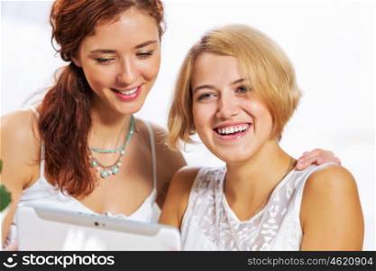 Two young ladies in cafe using tablet pc