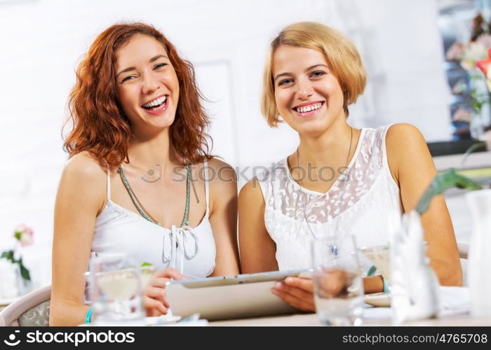 Two young ladies in cafe using tablet pc