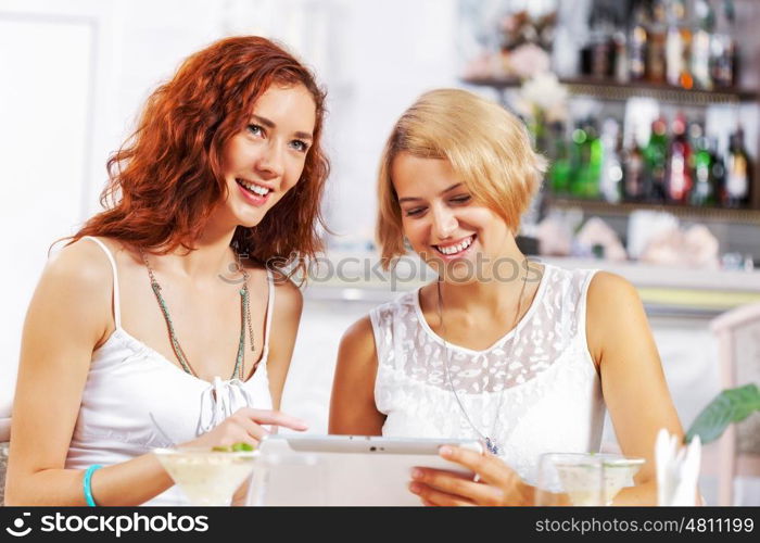 Two young ladies in cafe using tablet pc