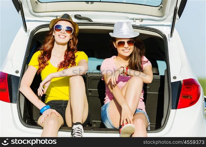 Two young ladies. Young happy young woman sitting in car trunk outdoor