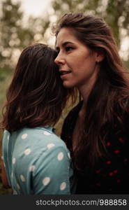 Two young lesbian women embraced on the field wearing dresses