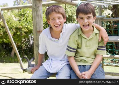 Two young male friends at a playground smiling