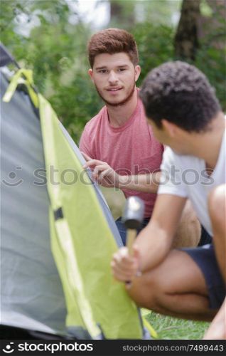 two young men assembling tent