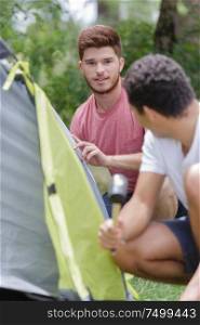 two young men assembling tent