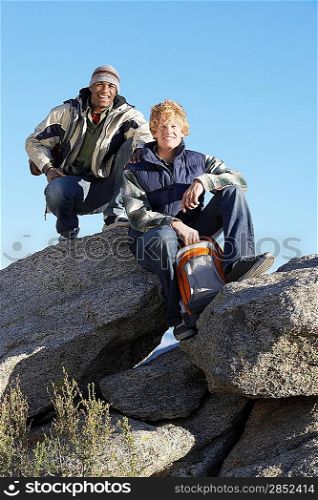 Two young men in warm clothing sitting on boulders