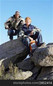 Two young men in warm clothing sitting on boulders