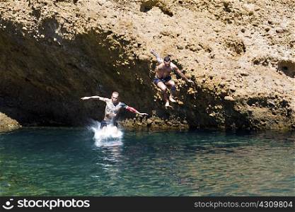 Two young men jumping into sea from rocks, Marseille, France