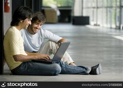 Two young men looking at a laptop and smiling