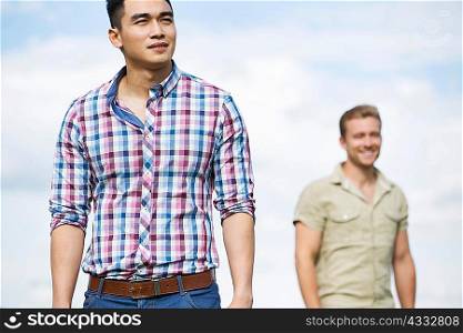 Two young men outdoors, focus on man in foreground