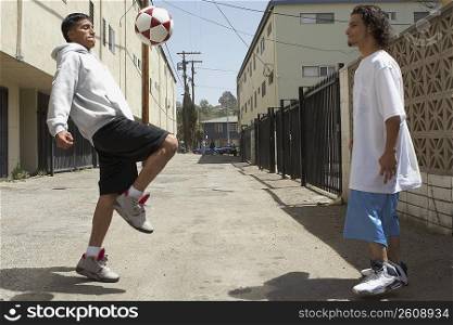 Two young men playing with a soccer ball on the street