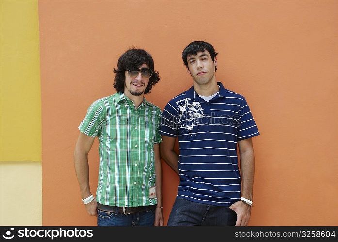 Two young men standing in front of a wall
