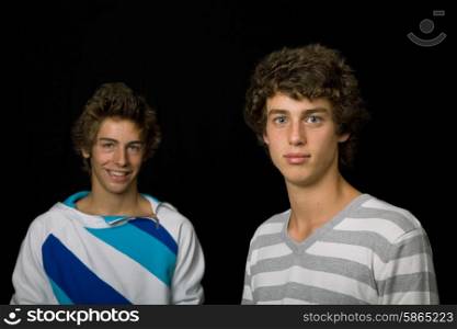 two young men standing, on a black background