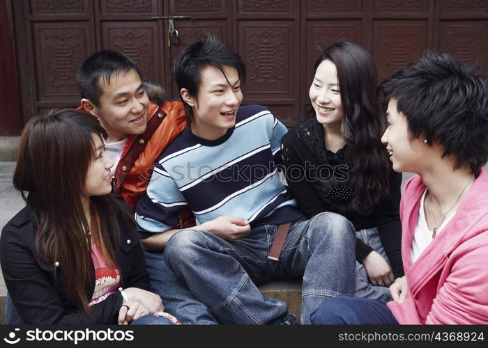 Two young men talking to two young women and a teenage boy