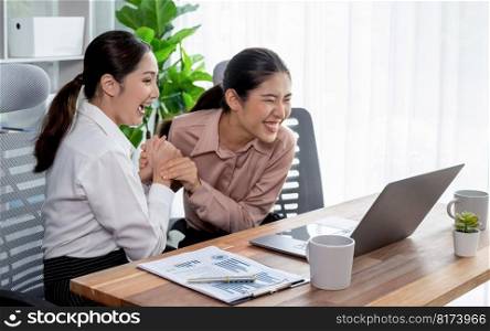 Two young office lady colleagues collaborating in modern office workspace, engaging in discussion and working together on laptop, showcasing their professionalism as modern office worker. Enthusiastic. Two young businesswoman work together in office workspace. Enthusiastic