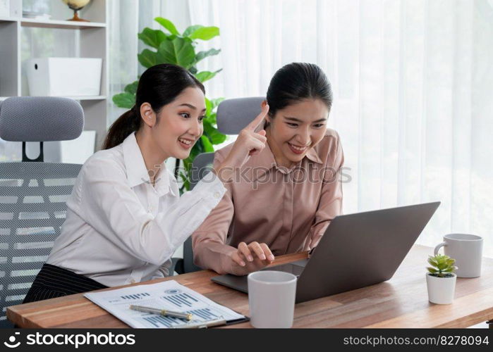 Two young office lady colleagues collaborating in modern office workspace, engaging in discussion and working together on laptop, showcasing their professionalism as modern office worker. Enthusiastic. Two young businesswoman work together in office workspace. Enthusiastic