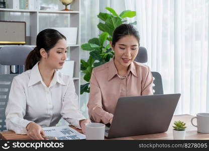 Two young office lady colleagues collaborating in modern office workspace, engaging in discussion and working together on laptop, showcasing their professionalism as modern office worker. Enthusiastic. Two young businesswoman work together in office workspace. Enthusiastic