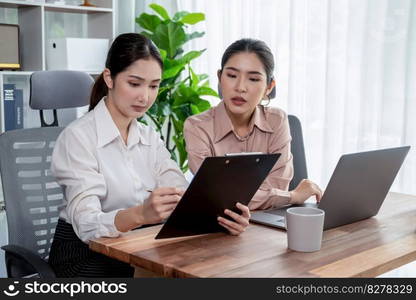 Two young office lady colleagues collaborating in modern office workspace, engaging in discussion and working together on laptop, showcasing their professionalism as modern office worker. Enthusiastic. Two young businesswoman work together in office workspace. Enthusiastic