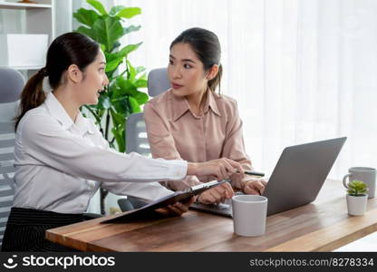 Two young office lady colleagues collaborating in modern office workspace, engaging in discussion and working together on laptop, showcasing their professionalism as modern office worker. Enthusiastic. Two young businesswoman work together in office workspace. Enthusiastic