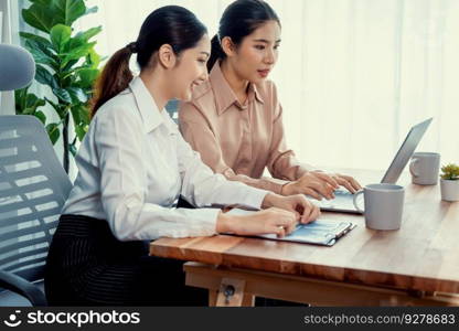 Two young office lady colleagues collaborating in modern office workspace, engaging in discussion and working together on laptop, showcasing their professionalism as modern office worker. Enthusiastic. Two young businesswoman work together in office workspace. Enthusiastic