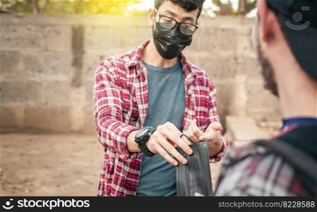 Two young people giving each other a mask, View of a young man giving a surgical mask to another person, concept of a person giving a surgical mask